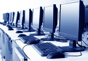 a row of computer monitors and keyboards in a computer lab